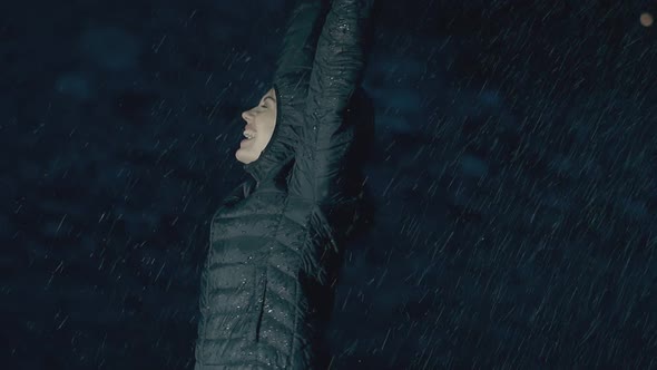 Young Woman in Green Jacket Smiles and Enjoys Heavy Rain