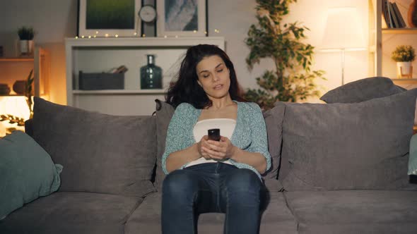 Cute Girl Turning on TV with Remote Control Watching Sitting on Sofa at Home