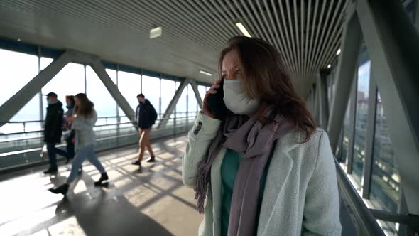 Adult Woman Is Calling By Mobile Phone Standing in Pedestrian Tunnel, Wearing Protective Face Mask