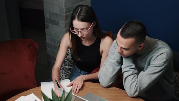 Businessman and Businesswoman Working with Papers on Couch in Home or Office.