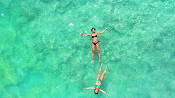 luxury vacation background. Two young women floating relaxing on the turquoise sea surface. Barbados