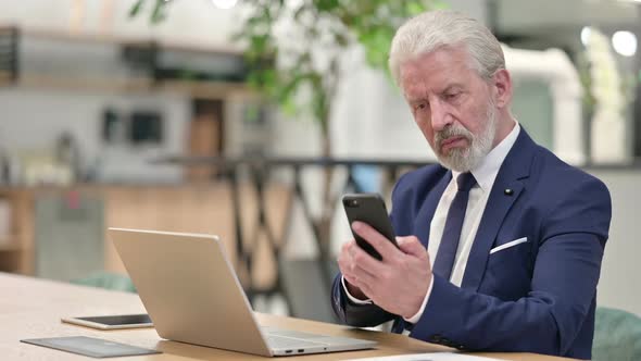 Senior Old Businessman with Laptop Using Smartphone