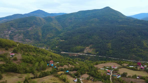 Steep green mountains, deep forest and mountain road, beautiful valley and village houses