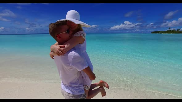 Family of two happy together on idyllic shore beach adventure by blue water with white sand backgrou