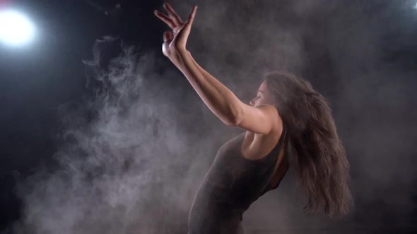Close-up of a Young Energetic Woman in a Black Suit in a Studio on a Black Background Dancing