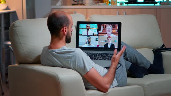 Tired Man Sitting Comfortable on Sofa While Chatting with Teammates