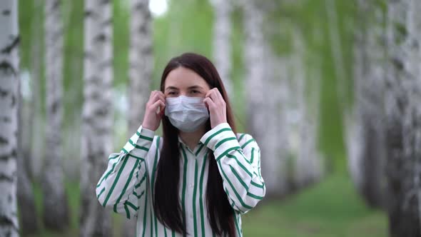 Young Woman Takes Off Medical Mask and Takes a Deep Breath in the Birch Grove