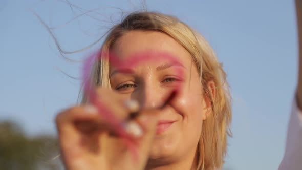 young artist paints a red heart on the glass.