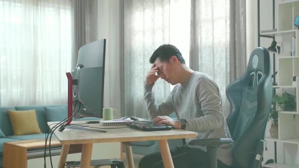 Asian Man Being Tired While Using The Desktop Computer For Working At Home
