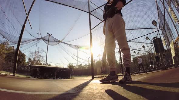 A baseball player practicing at the batting cages.