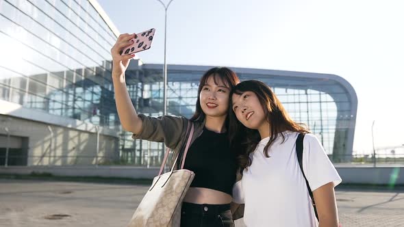 Exuberant Cute Asian Female Mates Making Selfie on the Airport Background