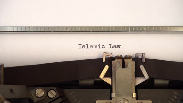 Typing phrase Islamic Law on retro typewriter. Close up.