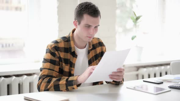 Excited Young Man Cheering After Reading Documents