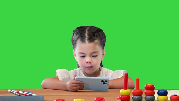 Small Girl Watching Something on Smartphone on a Green Screen Chroma Key