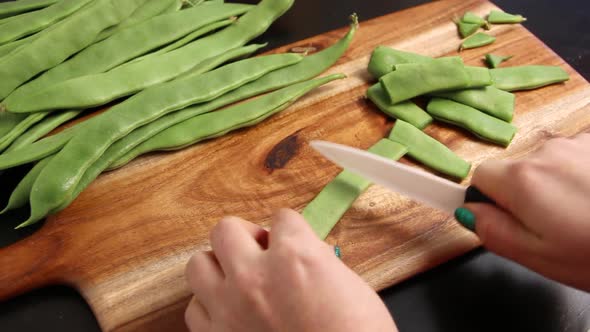 Woman's hands cutting piattoni green beans close up