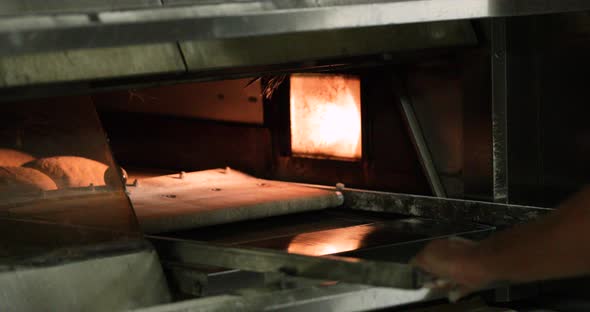 Baker Neatly Places Bread Tray In Oven For Baking - slow motion shot