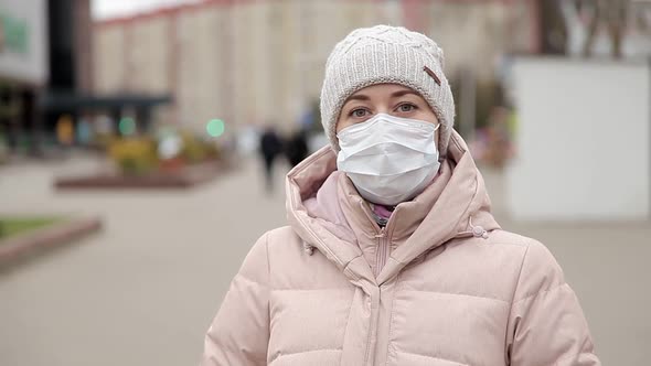 Woman Outdoors in a Public Place During an Outbreak of Coronavirus in a Medical Mask To Prevent