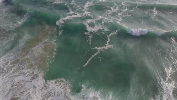 Beautiful ocean waves near shore churn up the sandy bottom, aerial