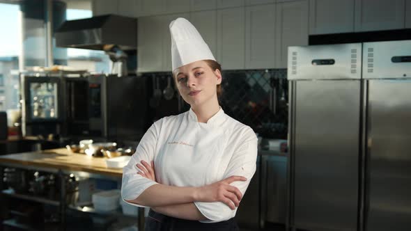 Professional kitchen portrait: Female Chef folds her arms and then laughs