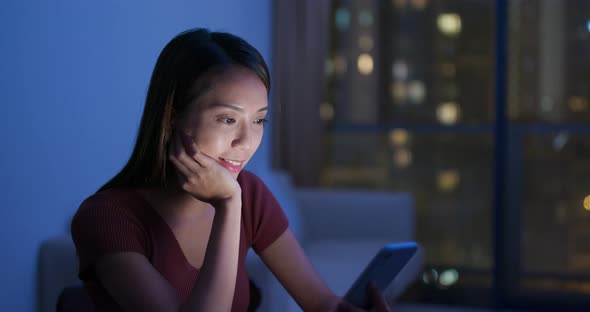 Woman use of mobile phone at home in the evening