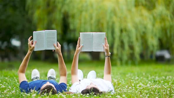 Relaxed Young Couple Reading Books While Lying on Grass