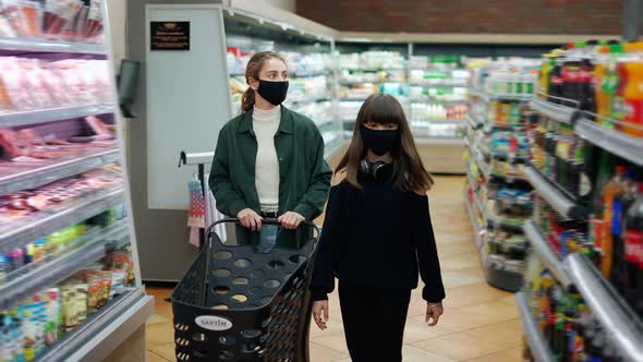 Teen Girl and Her Mom or Sister Shopping in the Supermarket with Cart Wearing Masks