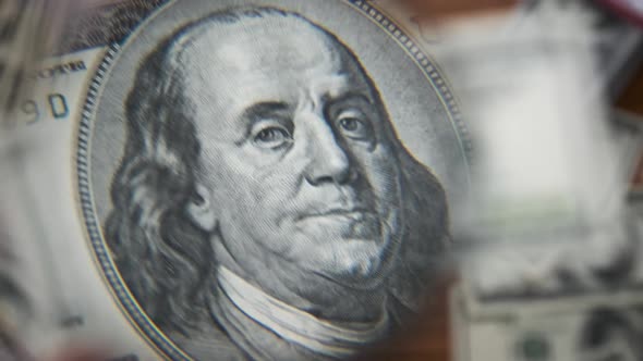 One Hundred Dollars Inspecting Under Magnifying Glass on Money Background