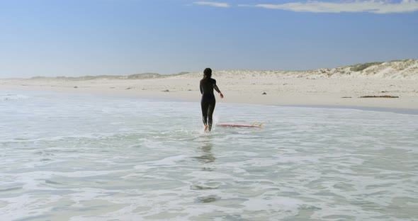 Woman running towards surfboard on the sea 4k