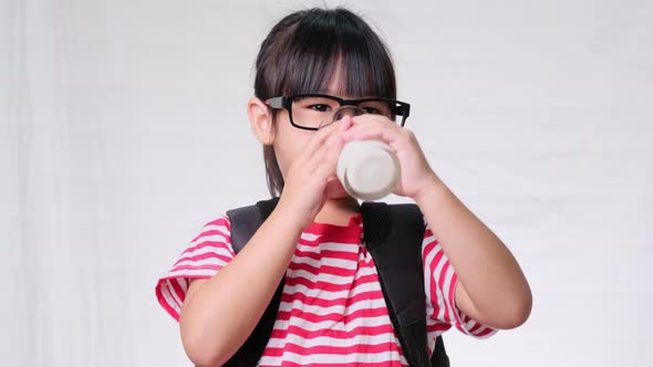 Cute schoolgirl drinking milk from a glass before going to school. Healthy nutrition for children. b