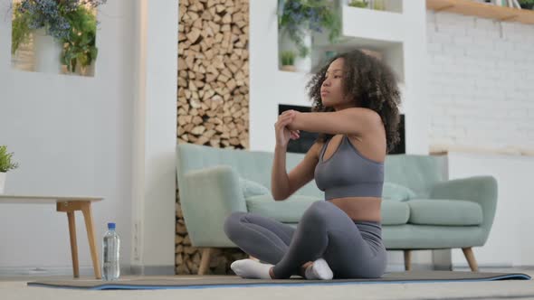 Young African Woman Doing Stretches on Yoga Mat at Home
