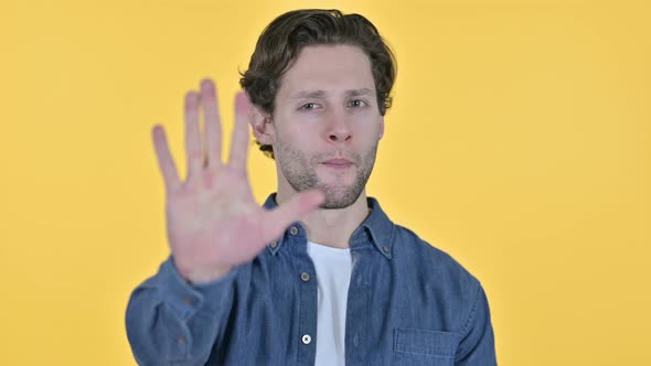 Stop Sign By Young Man, Hand Gesture on Yellow Background