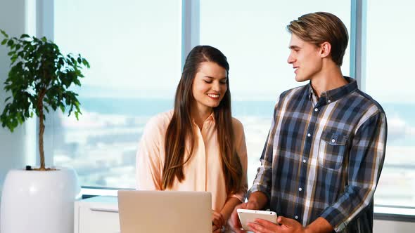 Executives interacting while using digital tablet and laptop