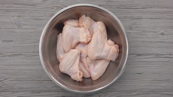 Top View of the Male Hands Sprinkling Chicken Wings with Spices