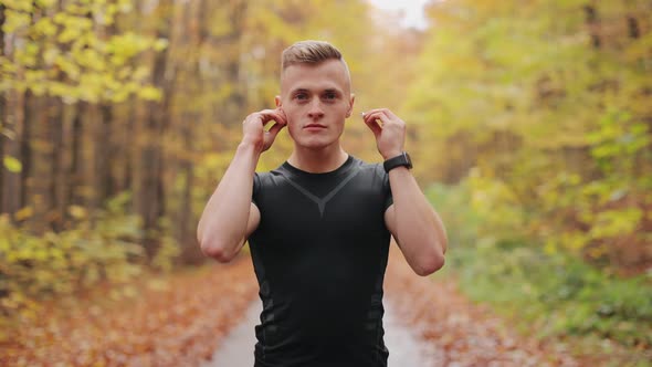The Athlete is Standing on a Forest Road and Looking at the Camera