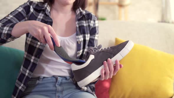 Young Woman Inserts an Orthopedic Insole Into the Shoe Close Up