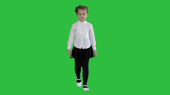 Little serious girl walking towards camera on a Green Screen