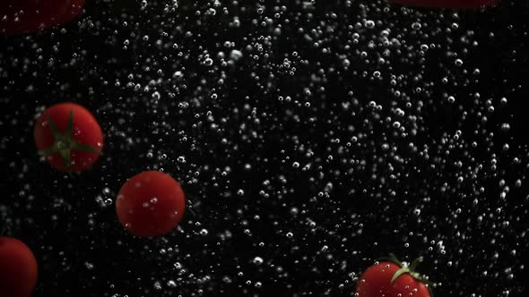 Ripe Vegetables Cherry Tomatoes and Bell Pepper Falling Into Water Black Background