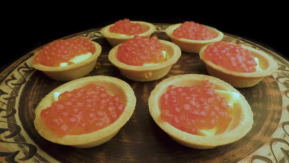 Red Caviar Is Put with a Spoon on Tartlets. Preparation of Snacks with Red Caviar. Top View