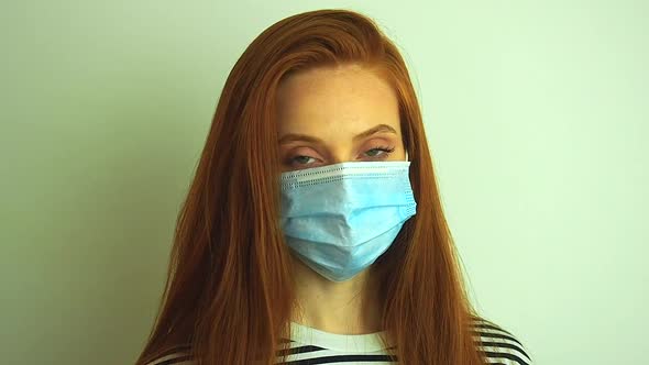 Young Woman Wears Protective White Medical Mask Puts on Medical Gloves and Glasses Preparing for