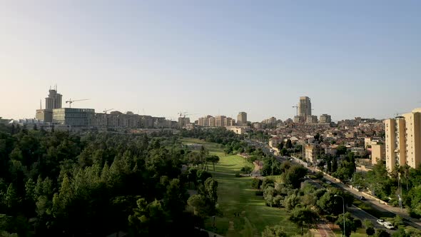 Aerial forward fly over Sachet park in Jerusalem, tall buildings on the right hand side, forward dro