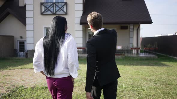 Tracking Shot of Elegant Real Estate Agent Walking with Client to New House Talking Gesturing in