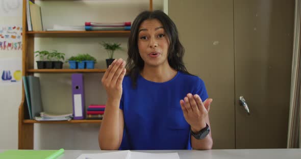 Mixed race female teacher sitting at desk having video call