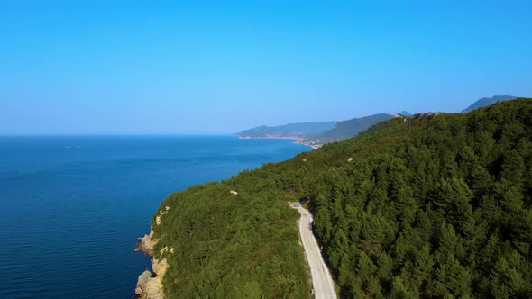 Steep green mountains, deep forest and mountain road, beautiful valley and blue sea