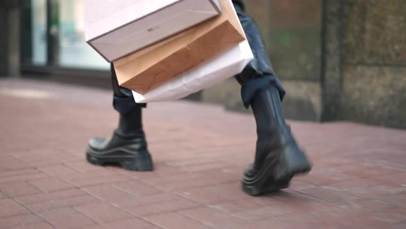 Live Camera Follow Legs of Young Fashionable Man in Leather Pants and Shoes Strolling with Shopping