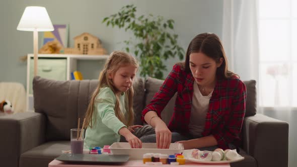 Teenage and Little Girls Color Boiled Eggs for Easter Feast