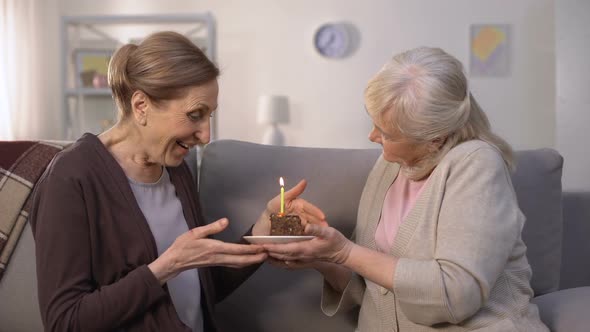 Mature Woman Presenting Birthday Cake to Her Sister, Happy Lady Blowing Candle