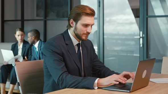 Working man in a suit with a laptop in the office. Young businessman at work