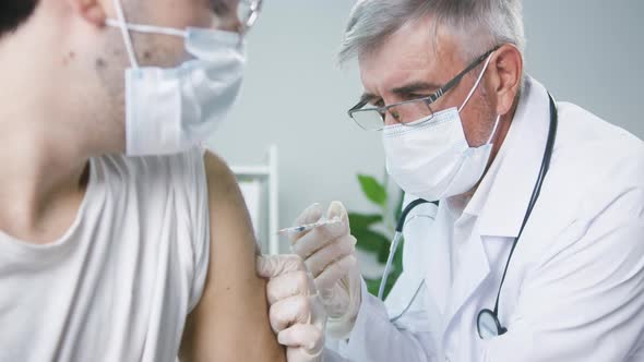 Coronavirus Vaccination Grafting in Polyclinic Aged Doctor and Young Man Patient in Protective Masks