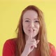 funny woman with red hair presses finger to her lips makes gesture of silence - VideoHive Item for Sale