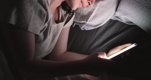 Young Woman Looking At Smart Phone And Lying On Bed. Close Up. High Angle